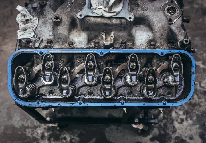 Detalle de balancines y resortes de un motor, con aceite visible, parte del sistema de lubricación.