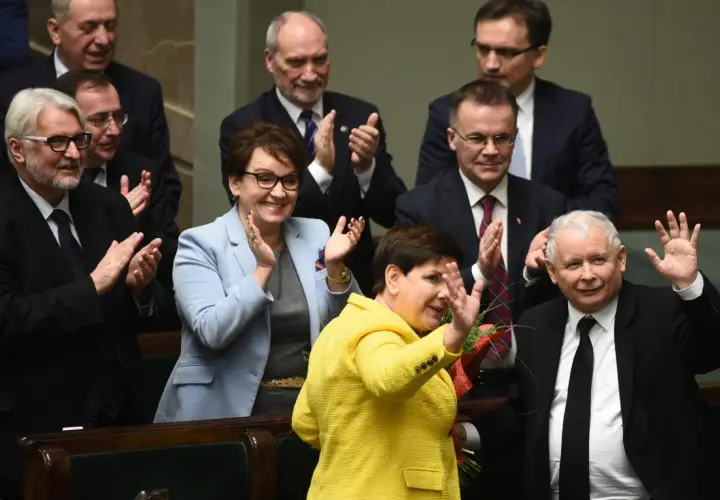 Kiedy rządził PiS, Beata Szydło w żółtej marynarce i Jarosław Kaczyński w garniturze pozdrawiają tłum.