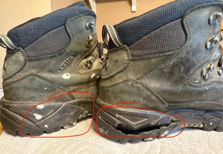 Two worn hiking boots with cracked and damaged soles, highlighted by red circles.