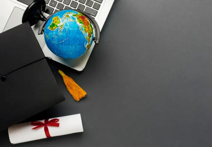 Dyplom, czapka absolwenta i globus na laptopie symbolizują globalne wykształcenie i nostryfikację.
