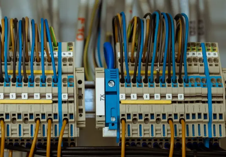 Starannie wykonane przyłącze elektryczne z wieloma przewodami w różnych kolorach, podłączonymi do zacisków.