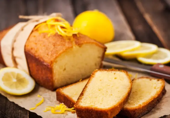 Babka piaskowa przepis babci, pachnąca cytryną, z kawałkami cytryny i skórką na drewnianym tle.
