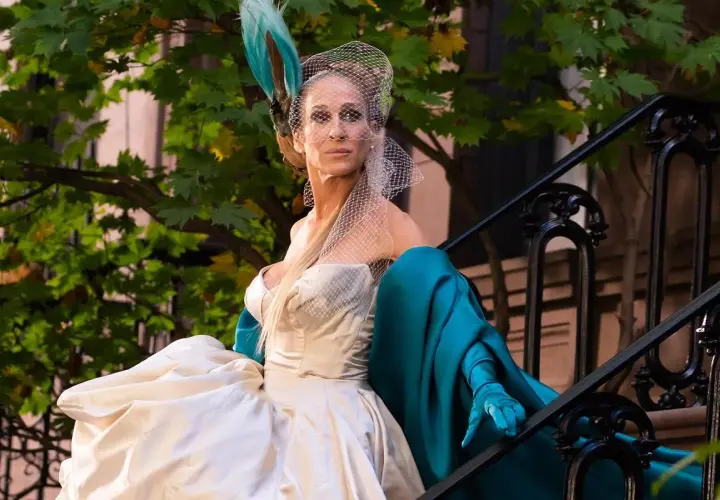Carrie Bradshaw w białej sukni i turkusowym płaszczu, z welonem na głowie, siedzi na schodach. I tak po prostu.
