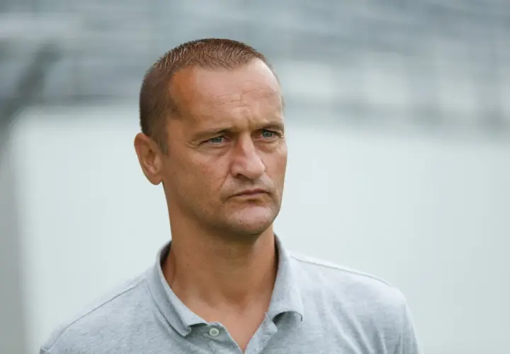 Dariusz Dźwigała w szarym polo, zamyślony, patrzy w bok.