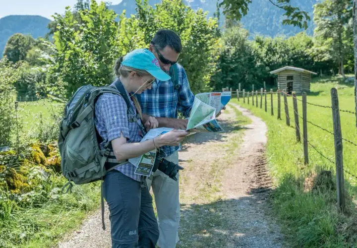 Zwei Wanderer mit Rucksäcken studieren eine Karte, um ihre Route zu planen. Die Packliste fürs Pilgern ist wichtig für die Tour.
