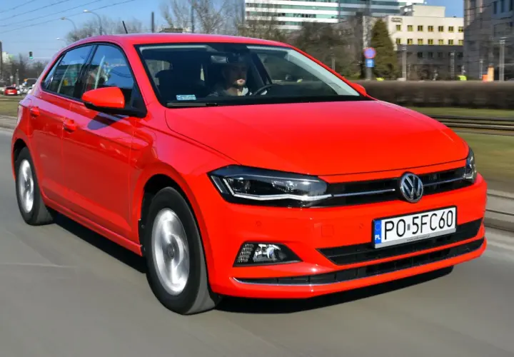 Czerwony Volkswagen Polo 6 w ruchu miejskim. Kierowca w szarej bluzie prowadzi auto.