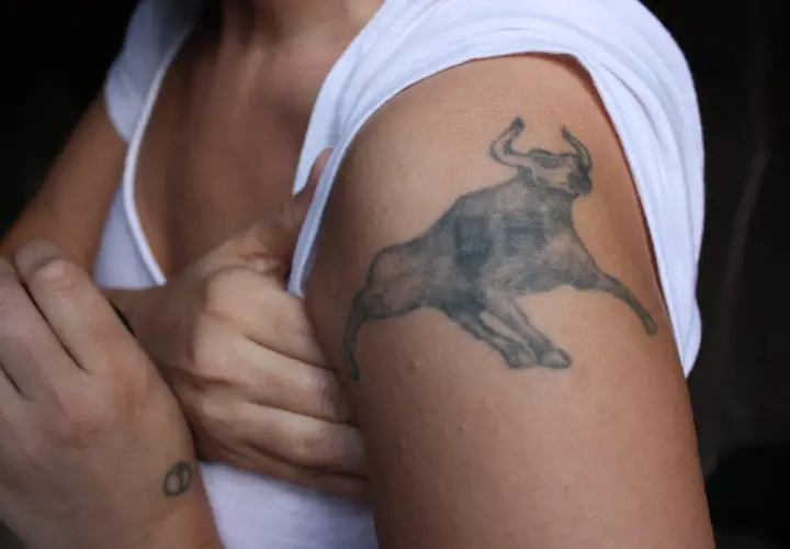 Mały tatuaż byk na ramieniu, symbol siły i odwagi.