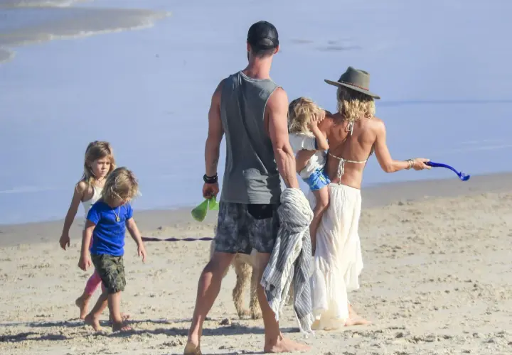 Chris Hemsworth z dziećmi i żoną na plaży. Rodzina cieszy się słońcem i piaskiem.