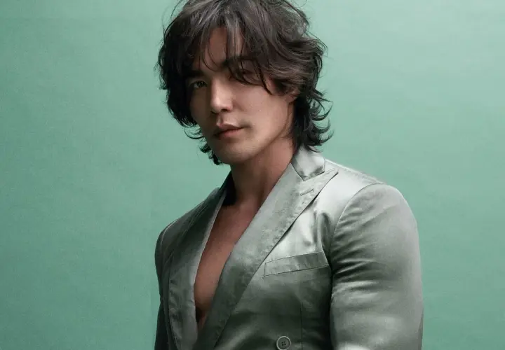 Ludi Lin, star de films et séries tv, pose dans un costume satiné sur fond vert menthe.