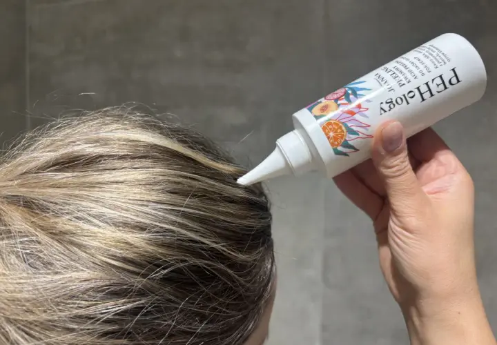 Aplikacja peelingu do skóry głowy z kwasami AHA na wilgotne włosy. Produkt w białej tubce z kolorowymi owocami.