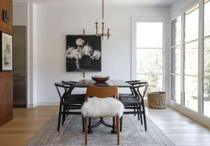 Modern dining room ideas: a dark wood table with black wishbone chairs, a floral painting, and a fluffy white accent chair.
