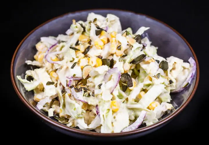 Frischer Chinakohl Salat mit Mais, roten Zwiebeln und Kürbiskernen in cremiger Soße.