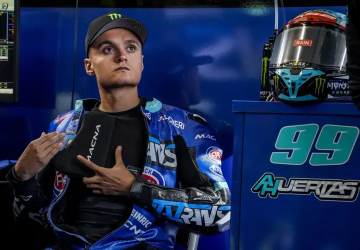Adrian Huertas, piloto de motociclismo, con su casco y mono azul. El número 99 destaca en el fondo.