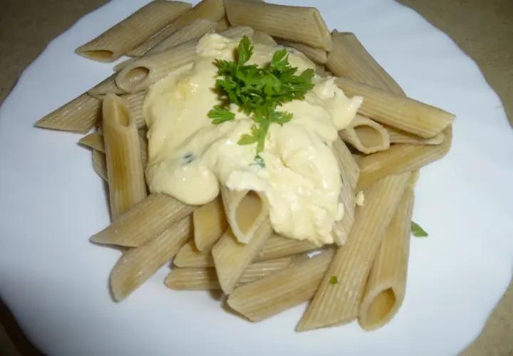 Penne z kremowym sosem pomidorowym z ricottą, udekorowane natką pietruszki. Pyszne danie gotowe w kilka minut.