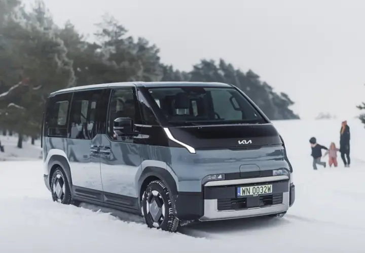 Nowy Kia PV5 w zimowej scenerii. Rodzina bawi się na śniegu w tle.