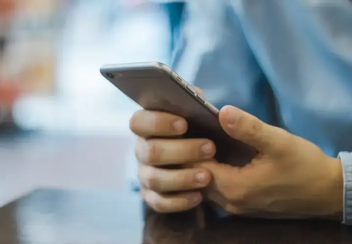 Mężczyzna trzyma telefon, zastanawiając się, jak zacząć rozmowę na Badoo.