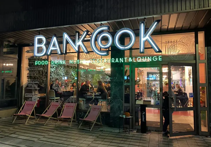 Klimatyczne restauracje Poznań: neonowy szyld "BANKOOK" nad wejściem, w środku ludzie przy stolikach.