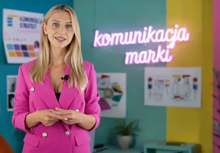 Kobieta w różowej marynarce wyjaśnia, jak przygotować się do pracy w branży marketingowej. W tle neon "komunikacja marki".