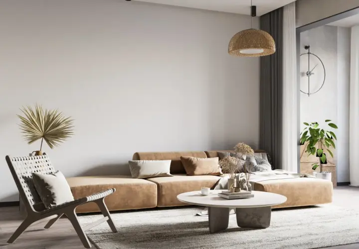 Salon w stylu wabi sabi: beżowa kanapa, pleciony fotel, suszone trawy i palma.