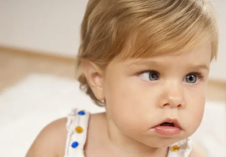 Primo piano di un neonato con occhi chiari. Uno sguardo attento, forse un caso di falso strabismo nei neonati, che spesso si risolve da solo.