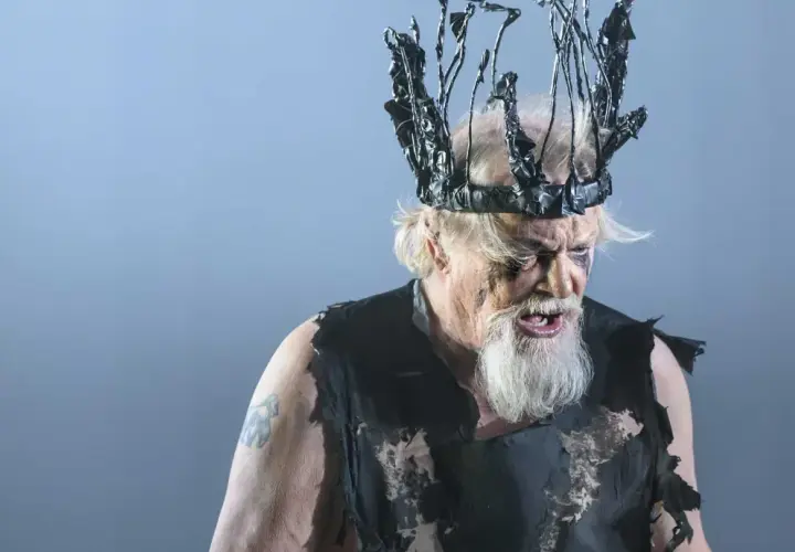 En skådespelare som Kung Lear på Dramaten, med en taggig, svart krona och trasiga kläder.