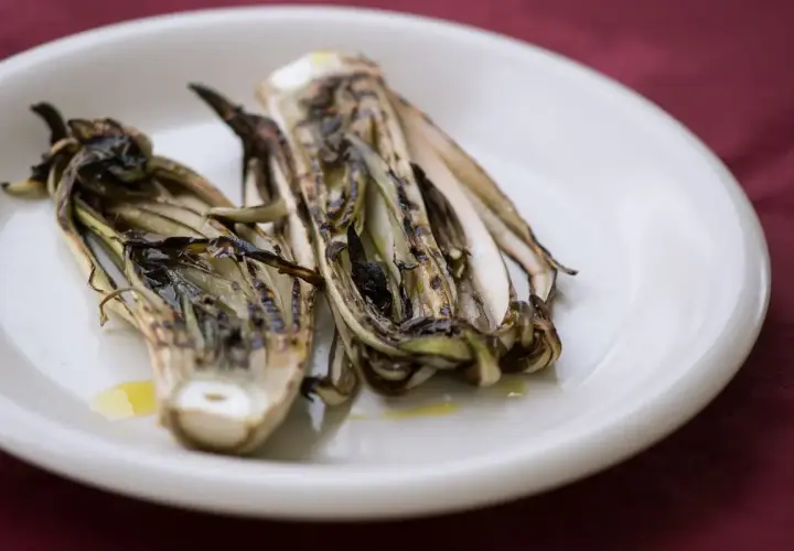 Radicchio grigliato in friggitrice ad aria, servito su un piatto bianco con un filo d'olio.
