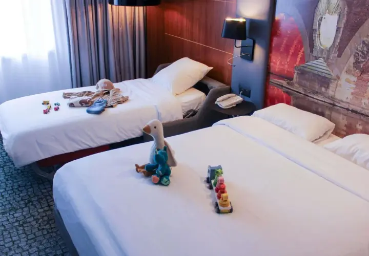Chambre d'hôtel avec deux lits, jouets et vêtements pour enfants.