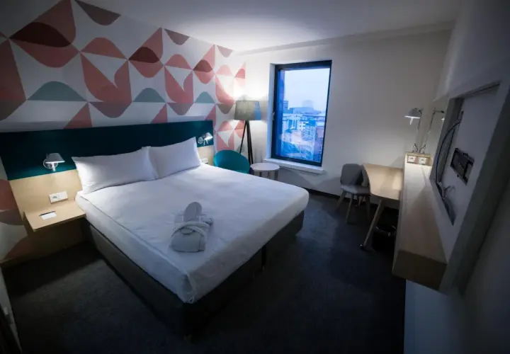 Przytulny pokój hotelowy z łóżkiem, szlafrokiem i widokiem na miasto. "Room only" to oferta bez wyżywienia.