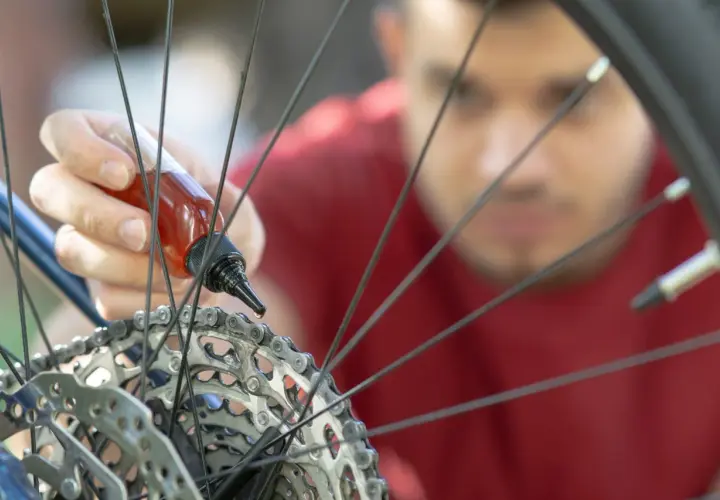 Mężczyzna aplikuje olej na łańcuch roweru, dbając o płynną jazdę. Smarowanie roweru to klucz do jego długowieczności.