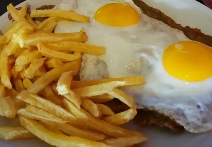Un delicioso plato de milanesa a caballo, con dos huevos fritos y papas fritas crujientes.
