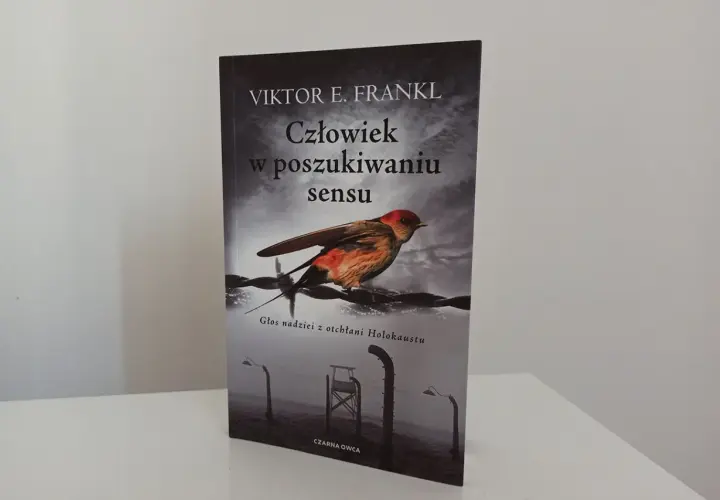 Okładka książki "Człowiek w poszukiwaniu sensu" Viktora Frankla. Ptak siedzi na drutach kolczastych, symbolizując nadzieję w mrocznych czasach.