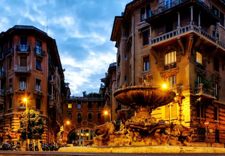 Fontana e palazzi illuminati a Roma, quartiere Coppedè cosa vedere. Atmosfera magica al crepuscolo.