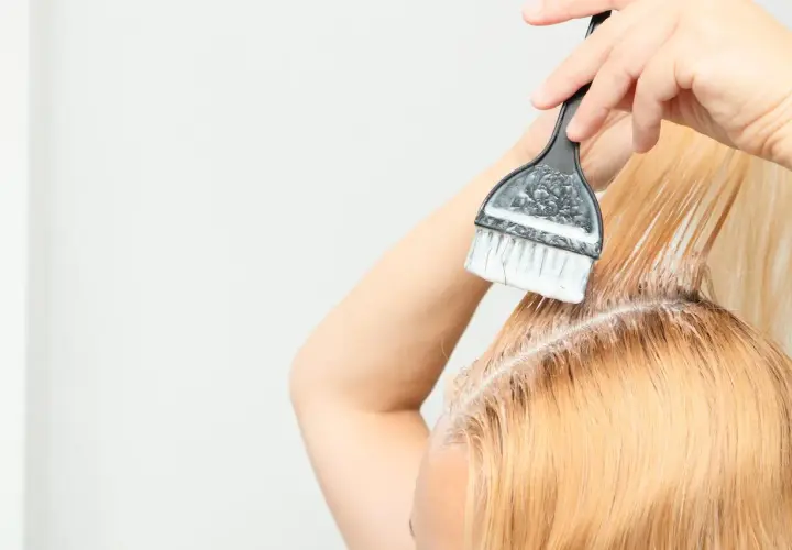 Persona se aplica tinta en el cabello, un proceso de tinta en casa para un cambio de look.
