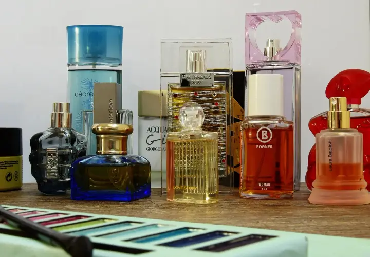 Różne flakoniki perfum i wód toaletowych na drewnianym blacie.