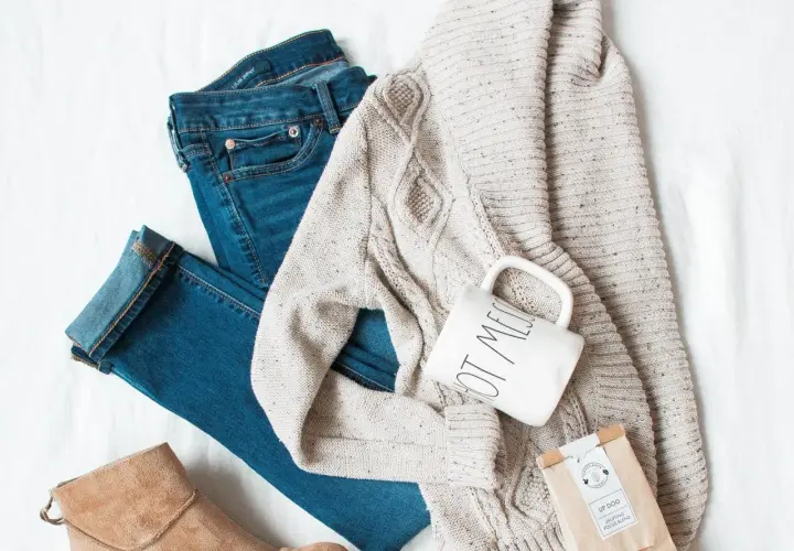 Un jean, un pull torsadé, une tasse et une botte en daim : un parfait style vestimentaire hiver pour une journée cosy.