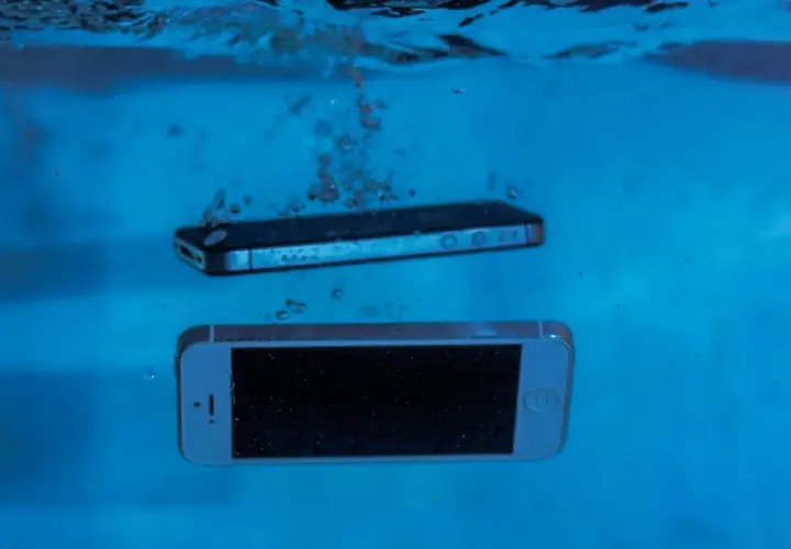 Dwa smartfony, jeden srebrny, drugi czarny, zanurzają się w wodzie. Ten wodoodporny smartfon przetrwa nawet takie zanurzenie.
