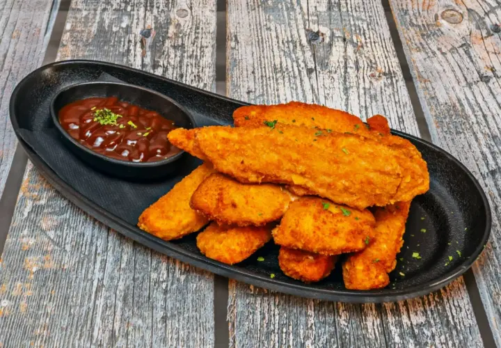 Chrupiący kurczak w panko, podany z sosem barbecue na czarnej tacy. Idealna przekąska.