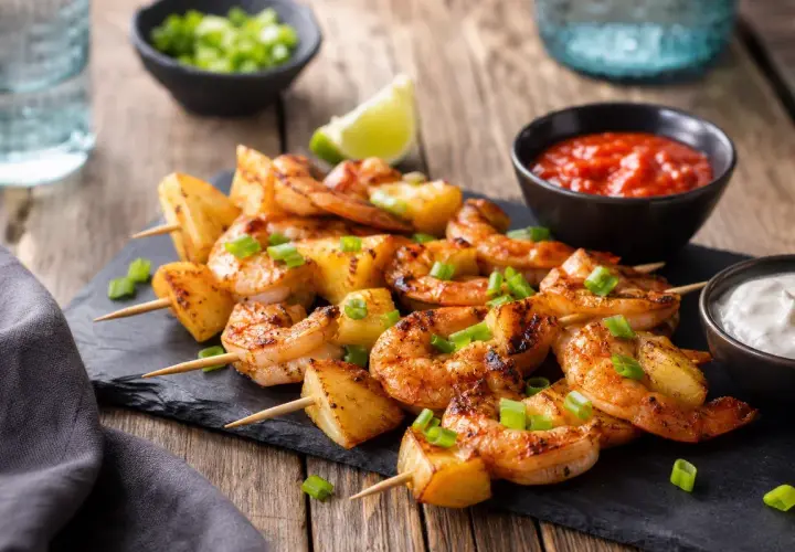 Brochettes de crevettes grillées et d'ananas, garnies de ciboule. Une excellente idée repas de décembre, servie avec sauce piquante et sauce blanche.