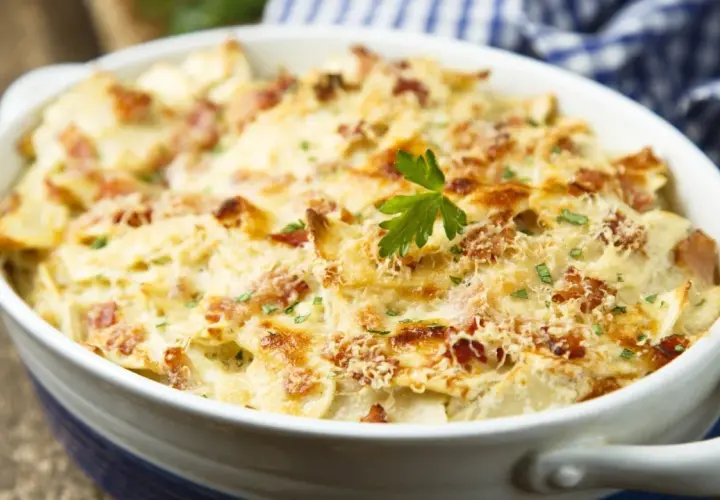 Un plat de tartiflette gratinée, garni de lardons et de persil, prêt à être dégusté avec un bon vin.
