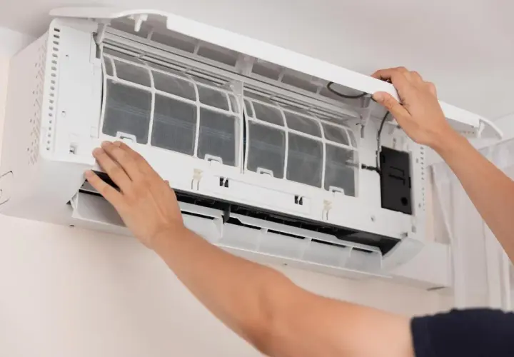 Man opens air conditioner to clean filters. Dirty filters can cause why the air conditioner freezes.