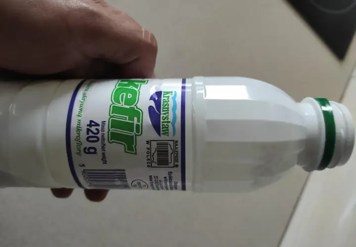 Butelka kefiru Krasnystaw 420g, z zieloną zakrętką, trzymana w dłoni.