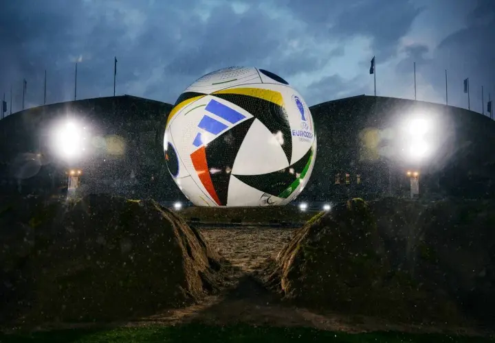 Gigantyczna piłka mistrzostw europy, symbol nadchodzącego turnieju, lśni w deszczu przed stadionem.