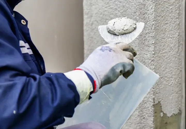 Pracownik nakłada tynk silikonowy. Sprawdź aktualną cenę za m2 robocizny i ciesz się nową elewacją.
