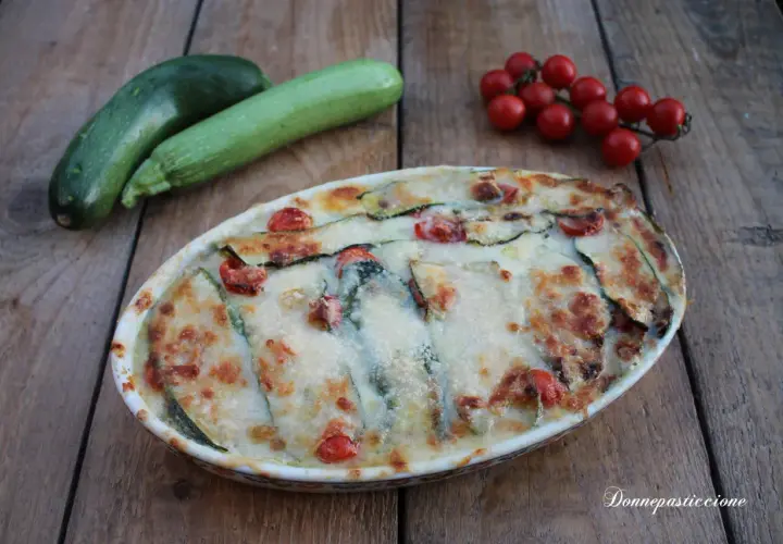Parmigiana di zucchine non fritte, con pomodorini e formaggio filante, pronta per essere gustata.