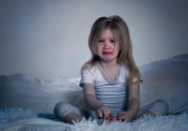 Verängstigtes Kind weint im Bett. Ein kleiner Junge hat einen Nachtschreck. Was tun?