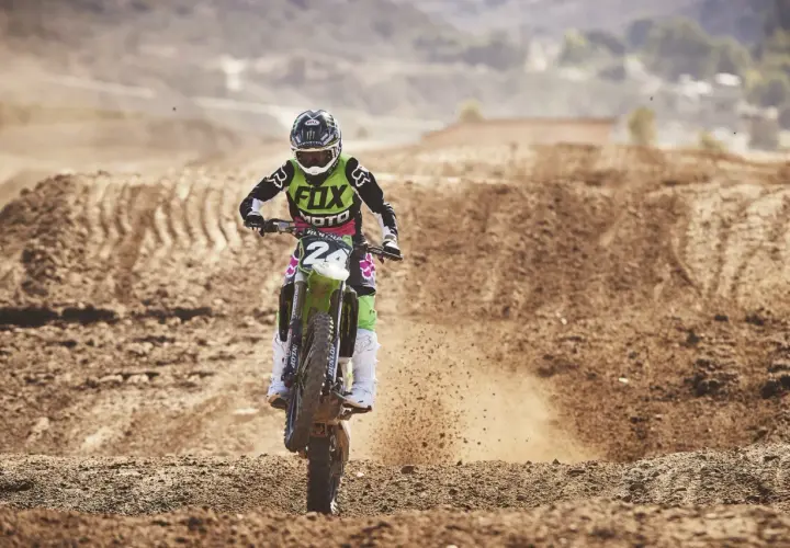 Motocrossowy zawodnik w stroju z logo Fox, jak prawdziwy fox titan, pędzi po piaszczystym torze, wzbijając tumany kurzu.