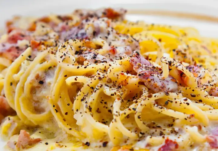 Spaghetti alla carbonara tradizionali, un piatto cremoso con guanciale croccante e abbondante pepe nero.