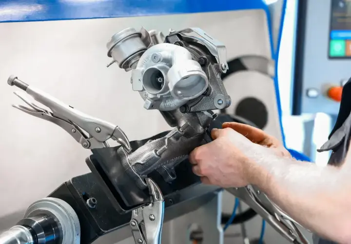 Mechanik pracuje nad turbosprężarką, przygotowując ją do czyszczenia n75. Urządzenie jest zamocowane w imadle.