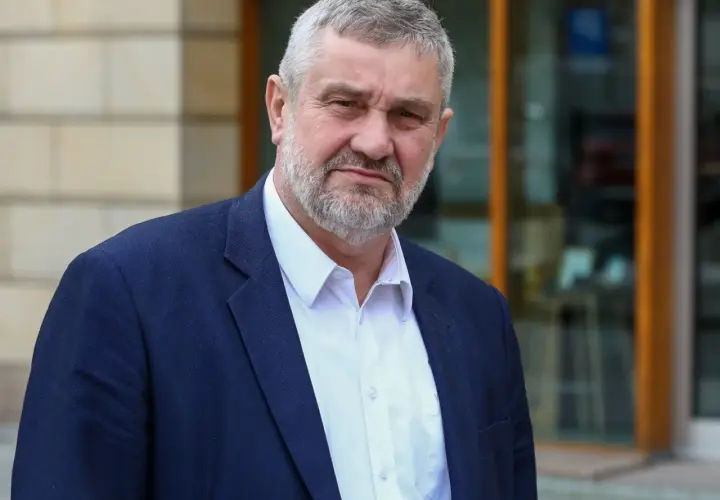 Mężczyzna z siwą brodą w granatowej marynarce i białej koszuli. Czy pozna prawdę o zarzutach prokuratorskich dla byłego ministra rolnictwa w 2025 roku?