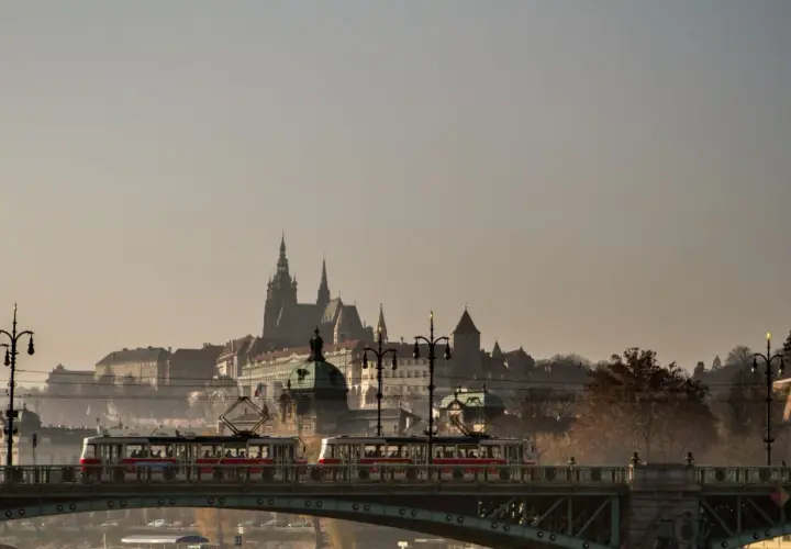 Most w Czechach z tramwajami na tle zamku.